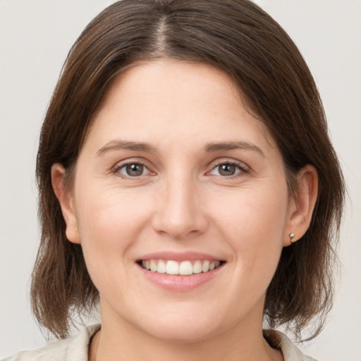 Joyful white young-adult female with medium  brown hair and grey eyes