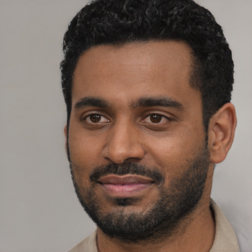 Joyful black young-adult male with short  black hair and brown eyes