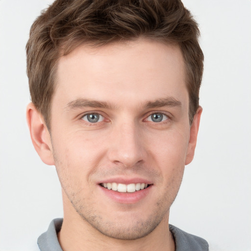 Joyful white young-adult male with short  brown hair and grey eyes