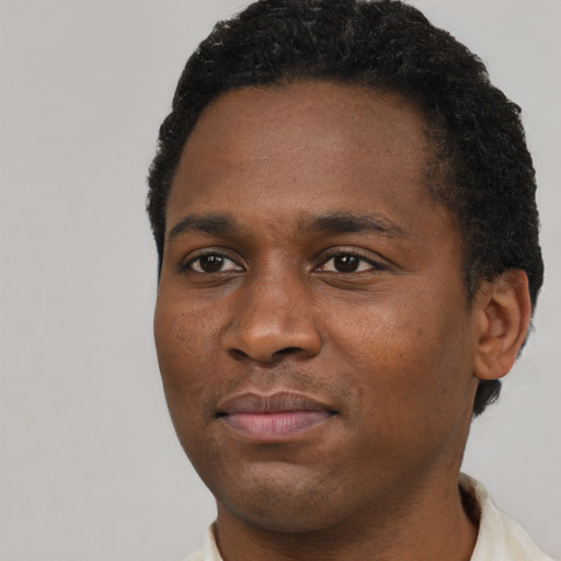 Joyful black young-adult male with short  brown hair and brown eyes