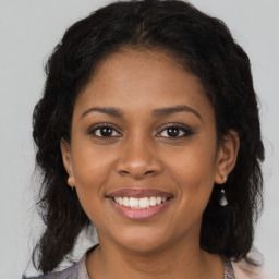 Joyful black young-adult female with long  brown hair and brown eyes