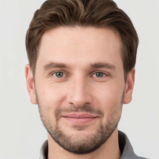 Joyful white young-adult male with short  brown hair and grey eyes