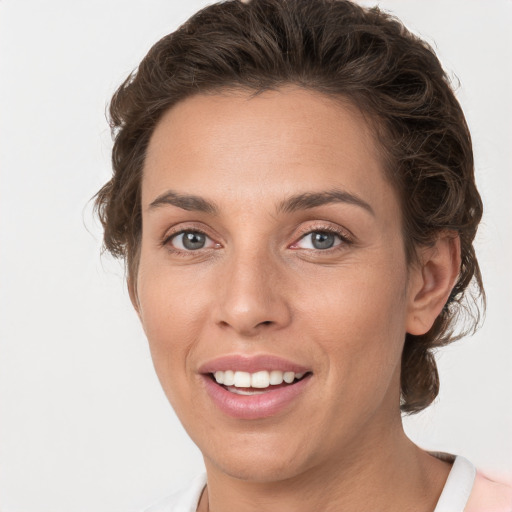 Joyful white young-adult female with medium  brown hair and grey eyes