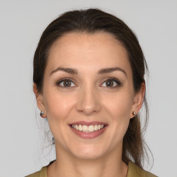 Joyful white young-adult female with medium  brown hair and grey eyes