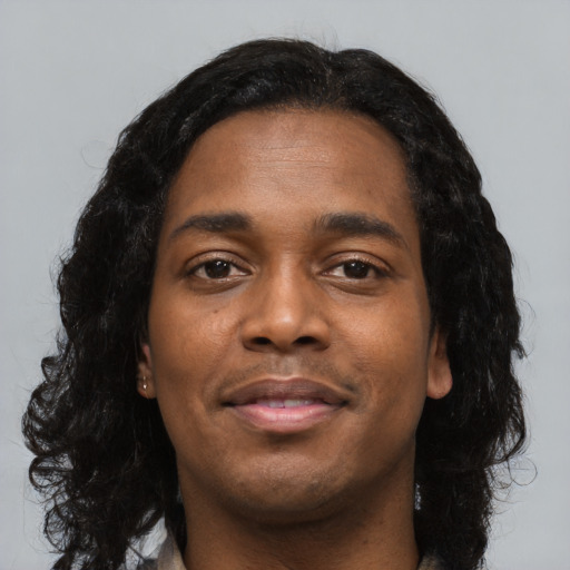 Joyful black young-adult male with long  black hair and brown eyes