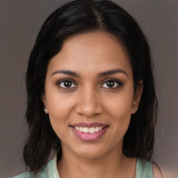 Joyful black young-adult female with long  brown hair and brown eyes