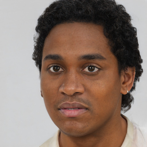 Joyful black young-adult male with short  brown hair and brown eyes