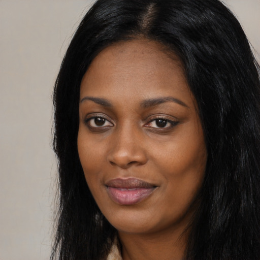 Joyful black young-adult female with long  black hair and brown eyes