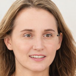 Joyful white young-adult female with long  brown hair and blue eyes